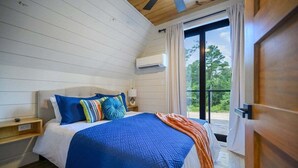 A bedroom with a bed, a nightstand, a window, and a door.