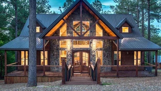 A log cabin with a central entrance, multiple windows, and a stone facade. - Arcade, Play Set, Hot Tub, Pets, Makin Plans (Broken Bow)