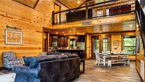 A spacious log cabin interior with a living area, dining space, and a kitchen. - Arcade, Play Set, Hot Tub, Pets, Makin Plans (Broken Bow)