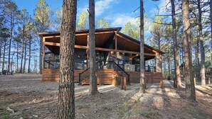 A cabin with a wooden exterior, multiple decks, and a fenced area. - Fenced Yard, Hot Tub, Fire pit, Swings, Pets, Surfing Sunsets (Broken Bow)