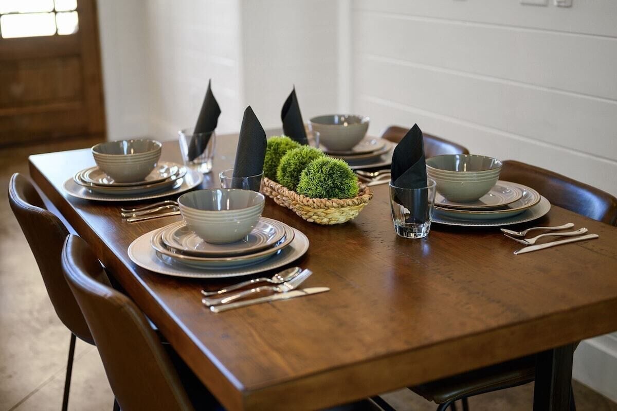 A dining table set with plates, bowls, cutlery, and napkins.