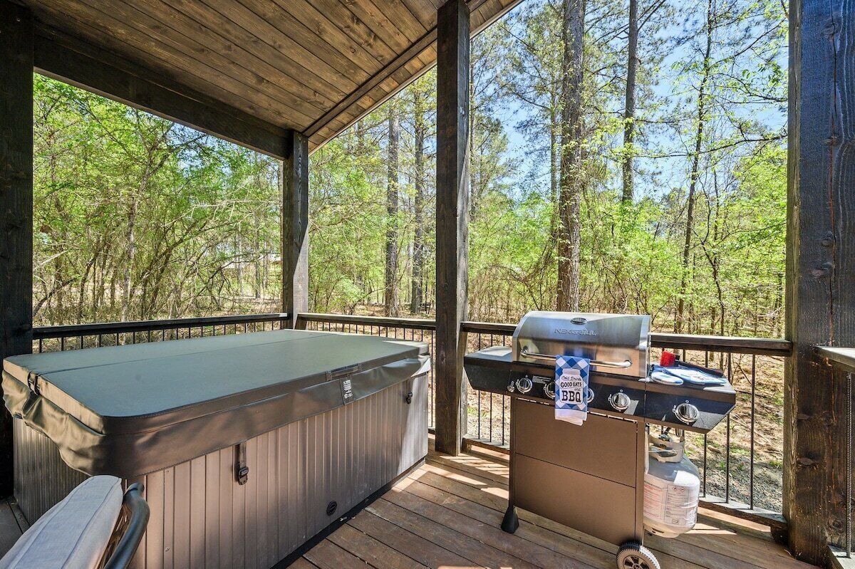 A covered outdoor area with a hot tub and a portable grill.