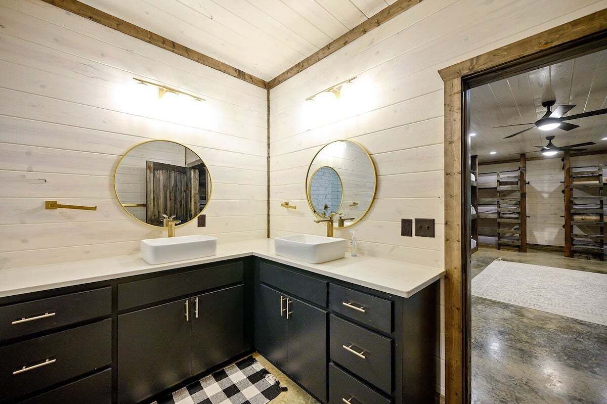 Un baño moderno con dos lavamanos, muebles oscuros y paneles de madera.