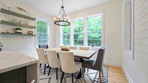 A dining area with a wooden table, white chairs, and a chandelier. - 2 Slides Off Deck, Foosball, Hot Tub, Pets, Let It Slide (Broken Bow)