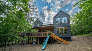 A two-story house with a deck, a slide, and a covered area. - 2 Slides Off Deck, Foosball, Hot Tub, Pets, Let It Slide (Broken Bow)