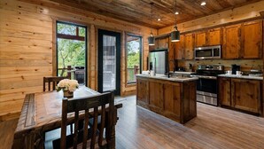 Une cuisine de style rustique, avec des éléments en bois, un îlot central, des appareils électroménagers intégrés et de grandes fenêtres.