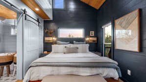 Ein Schlafzimmer mit einem großen Bett, einem Fenster mit Blick und einer Holzbalkendecke.