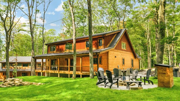 Une cabane en rondins dotée d’une terrasse et d’un espace salon extérieur.