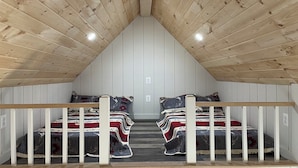 A small attic bedroom with two beds, wooden slats, and a white ceiling. - COZY CABIN. One room cabin with loft. Great sunsets & river view before Spring! (Great Cacapon)