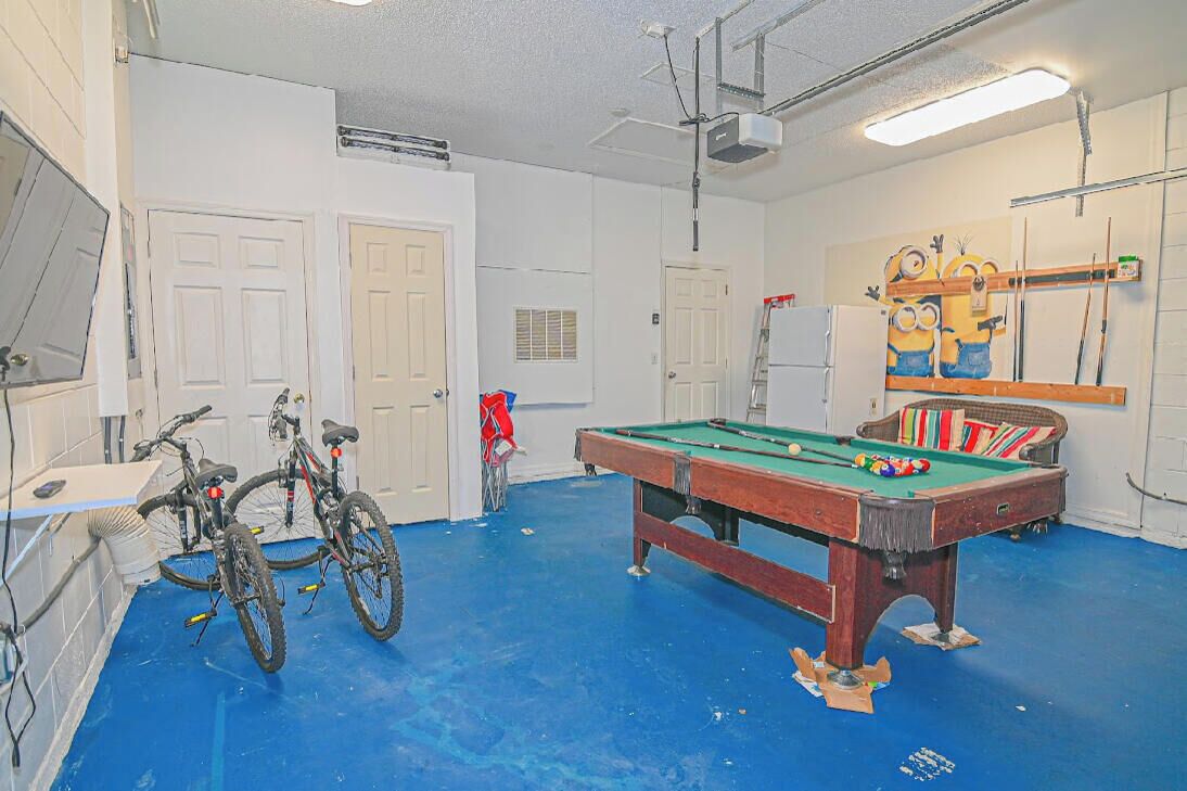 A room with a pool table, bicycles, and a Minion-themed wall decoration.