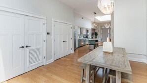 A spacious kitchen with white cabinetry, a wooden dining table, and a chandelier. - The Brazo - Central Downtown Cincinnati - walk to stadiums (cincinnati)