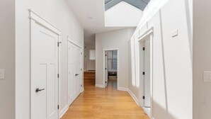 A corridor with white doors and wooden flooring, leading to a room with a skylight. - The Brazo - Central Downtown Cincinnati - walk to stadiums (cincinnati)