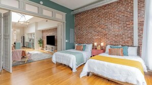 A spacious room with two beds, a brick wall, wooden flooring, and a ceiling fan. - The Brazo - Central Downtown Cincinnati - walk to stadiums (cincinnati)