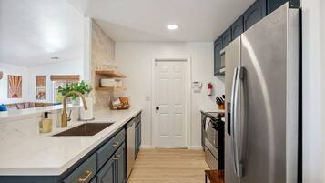 A modern kitchen with a stainless steel refrigerator, a sink, and a wooden countertop.
