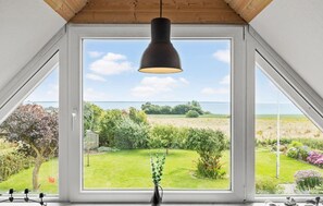 Una habitación con un ventanal grande que da a un jardín y una masa de agua.
