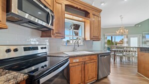 A kitchen with wooden cabinets, a stainless steel range, and a window overlooking a patio. - LARGE WATERFRONT HOUSE IN GULF SHORES, CLOSE TO EVERYTHING (Gulf Shores)