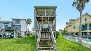 A multi-story building with a central staircase, surrounded by a grassy area and a pool. - LARGE WATERFRONT HOUSE IN GULF SHORES, CLOSE TO EVERYTHING (Gulf Shores)