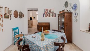 A dining area with a table set for four, a wooden cabinet, and a wall with a 'NEW YORK' sign. - GuestHost - Albachiara Home in Andria (Andria)