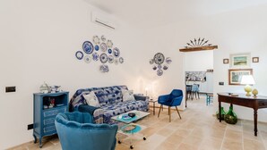A living room with a sofa, chairs, a coffee table, and wall decor. - GuestHost - Albachiara Home in Andria (Andria)
