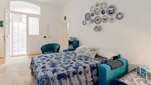 A bedroom with a bed, a chair, a wall-mounted air conditioner, and a door leading to a balcony. - GuestHost - Albachiara Home in Andria (Andria)