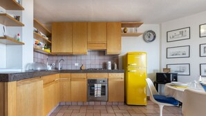 Eine kleine Küche mit Holzausstattung, einem gelben Kühlschrank, einer Spülmaschine und einem Essbereich mit einem Stuhl.