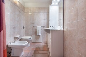 Une salle de bain équipée d’un bidet, de toilettes, d’un lavabo et d’un miroir.