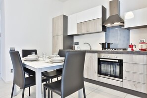 Een koelkast, een oven, een kookplaat, kookgerei, borden en bestek