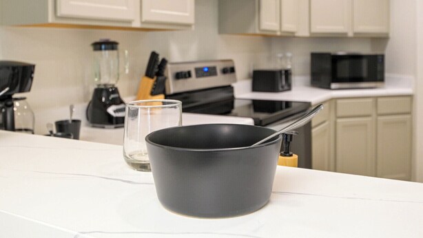 A kitchen with white cabinets, a black pot on the counter, and a glass. - SeaWorld San Antonio! Quiet, 4-bedroom house. 12 guests. (San Antonio)
