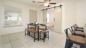 A dining area with a table set for four, benches, and a ceiling fan. - SeaWorld San Antonio! Quiet, 4-bedroom house. 12 guests. (San Antonio)