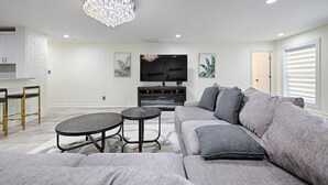 A modern living room with a grey sofa, a round coffee table, a TV, and a chandelier. - enjoy ranch life.

 (Allen)