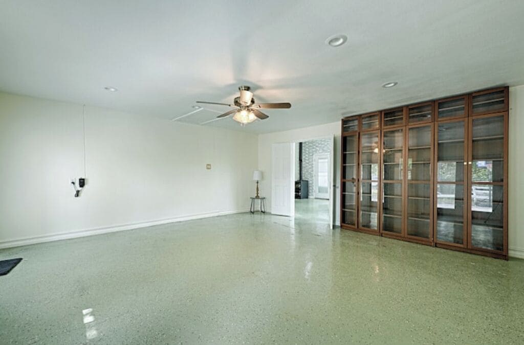 A spacious room with a polished floor, a ceiling fan, and a large sliding glass door.
