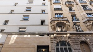 Un edificio que combina una fachada moderna con una sección clásica, adornada con detalles ornamentales y balcones.