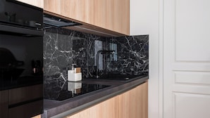 Una cocina moderna con salpicadero de mármol negro, armarios de madera y una encimera negra elegante.