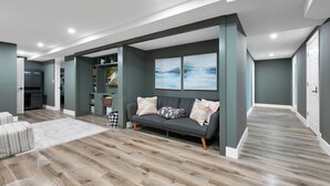 Un salon moderne avec un canapé gris, un plancher en bois et une bibliothèque.