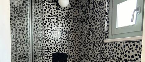A bathroom with a polka dot tile design, a toilet, a sink, and a shower area.