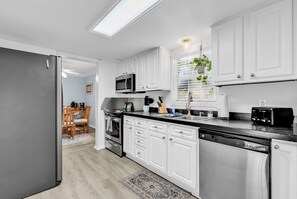 A modern kitchen with white cabinets, stainless steel appliances, and a black countertop. - 5 golf courses within 5 mins, 5 mins from beach, 15 mins from Murrells Inlet (Pawleys Island)
