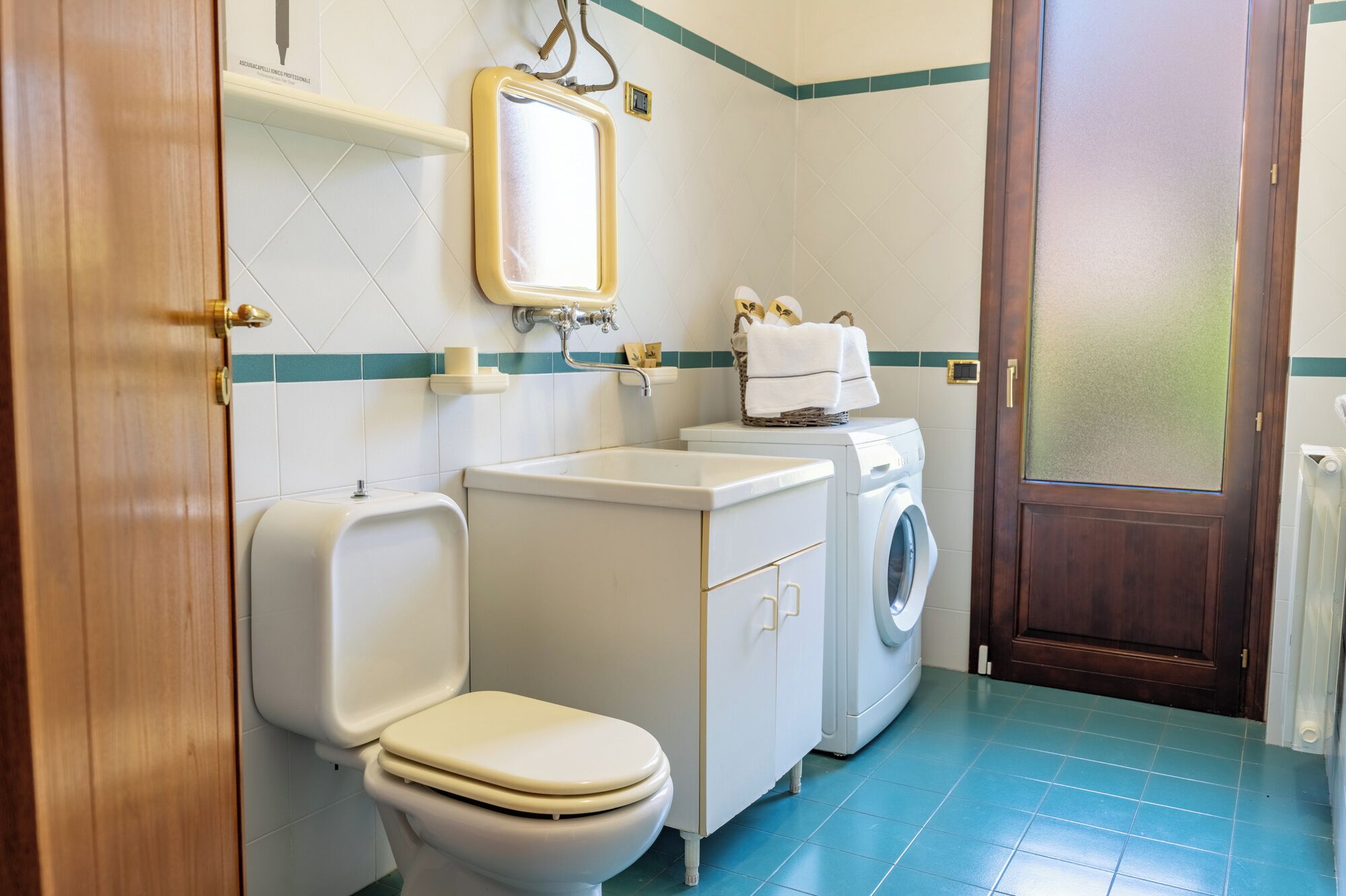 Une petite salle de bain comprenant des toilettes, un lavabo et un lave-linge.