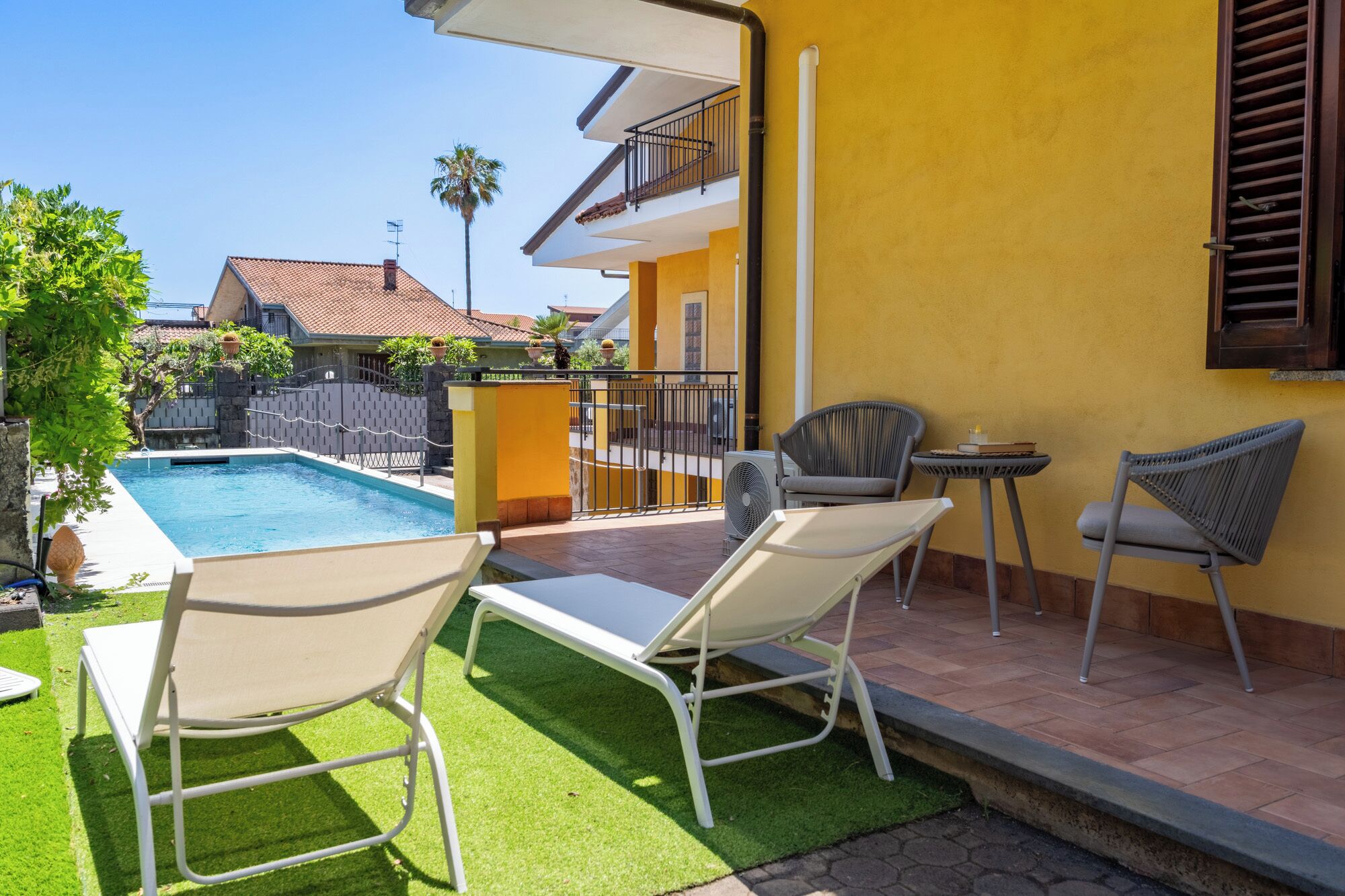 Un espace aménagé au bord de la piscine, comprenant deux chaises longues, une petite table et une chaise.