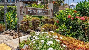 A sign for 'Kihei Alii Kai' at 2387 S. Kihei Rd. with a landscaped garden featuring various plants and flowers.