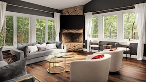 A modern living room with a fireplace, large windows, and a cozy seating area.
