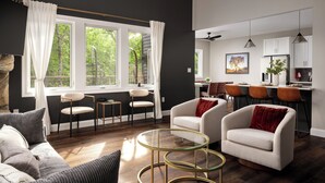 A modern living room with a sofa, armchairs, a glass coffee table, and a dining area with bar stools.