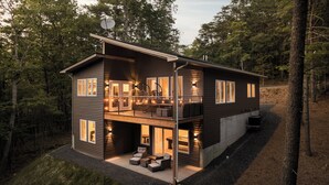 A two-story cabin with a balcony, large windows, and a satellite dish.