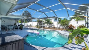 Une piscine extérieure couverte, dotée d’une terrasse en bois, de chaises longues et d’un espace patio.