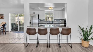 Une cuisine moderne avec un îlot central, des tabourets de bar et une plante en pot.