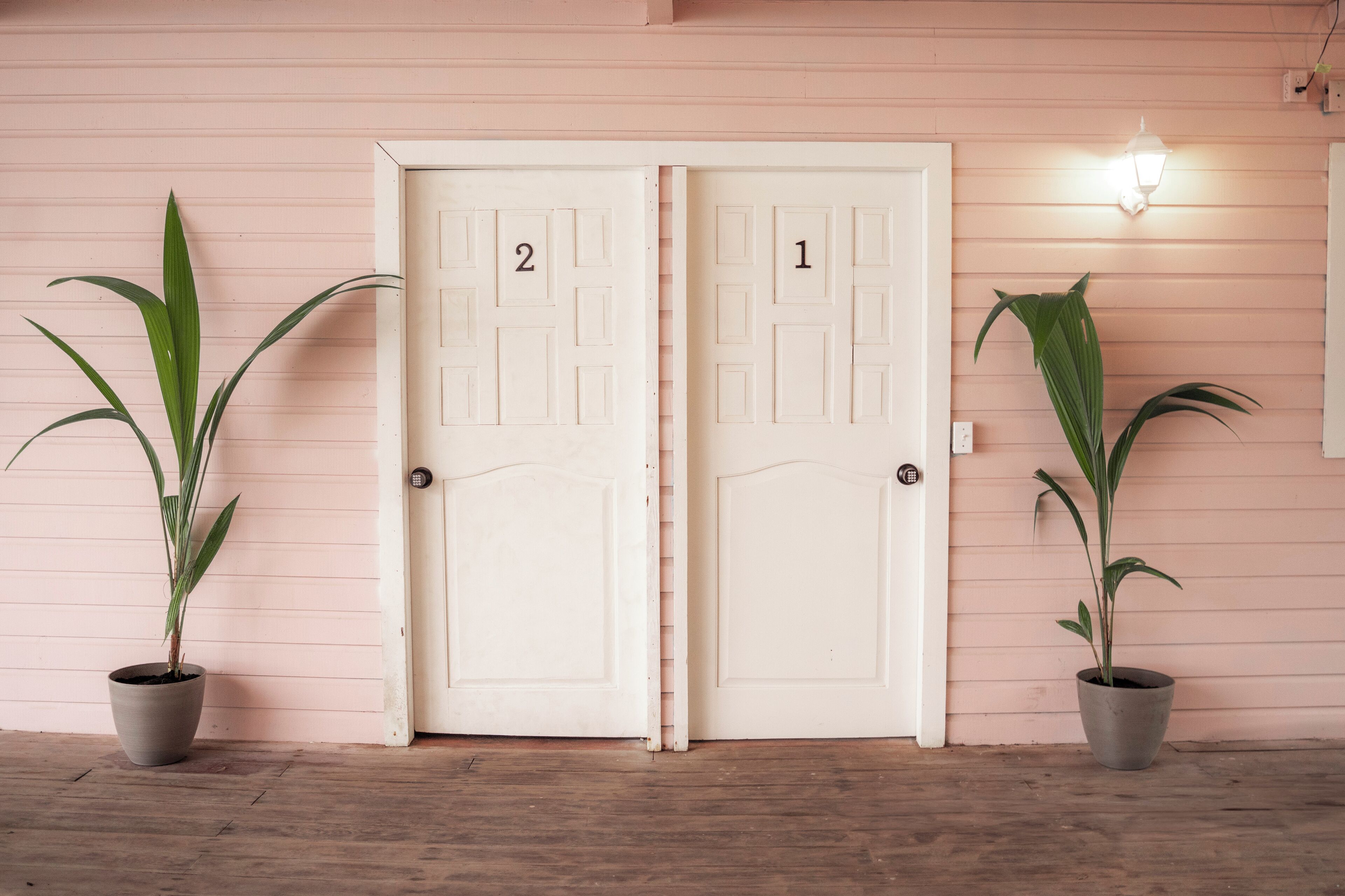 Two doors labeled 1 and 2, flanked by potted plants, with a light fixture above door 1.