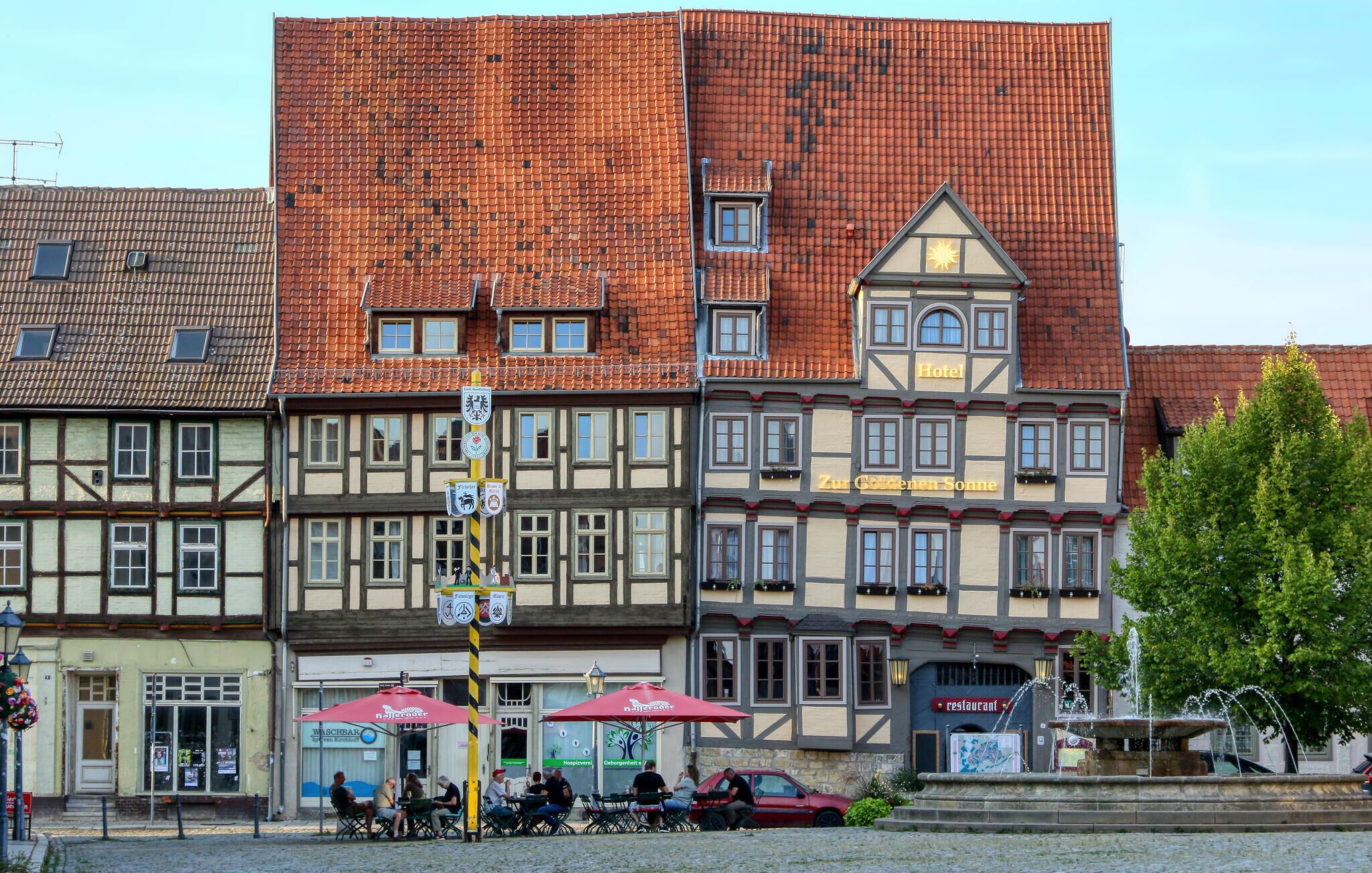 Um hotel tradicional europeu com telhado de telhas vermelhas, várias janelas e uma placa indicando ser um hotel.