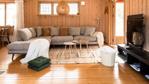 Una sala acogedora con un sofá modular, una mesita redonda, un televisor y una estantería.