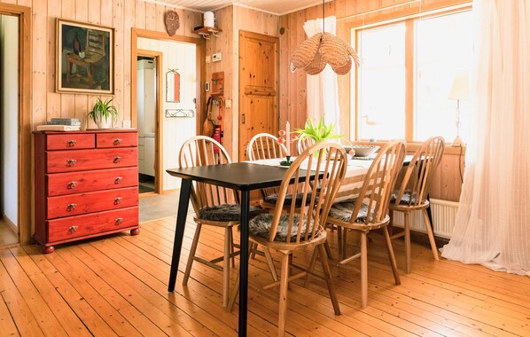 A wooden dining room with a table and chairs, a red dresser, and a painting on the wall. - 4 bedroom lovely home in Fagerfjäll (Fagerfjäll)
