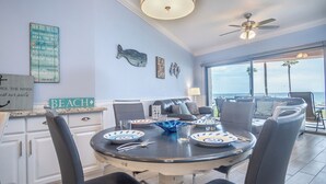 A dining area with a round table, chairs, and a view of the ocean.