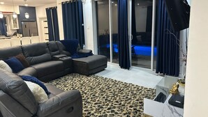 A modern living room with a sectional sofa, a glass door leading to a pool, and a flat-screen TV mounted on the wall. - St. Rose Villa (Savannes)